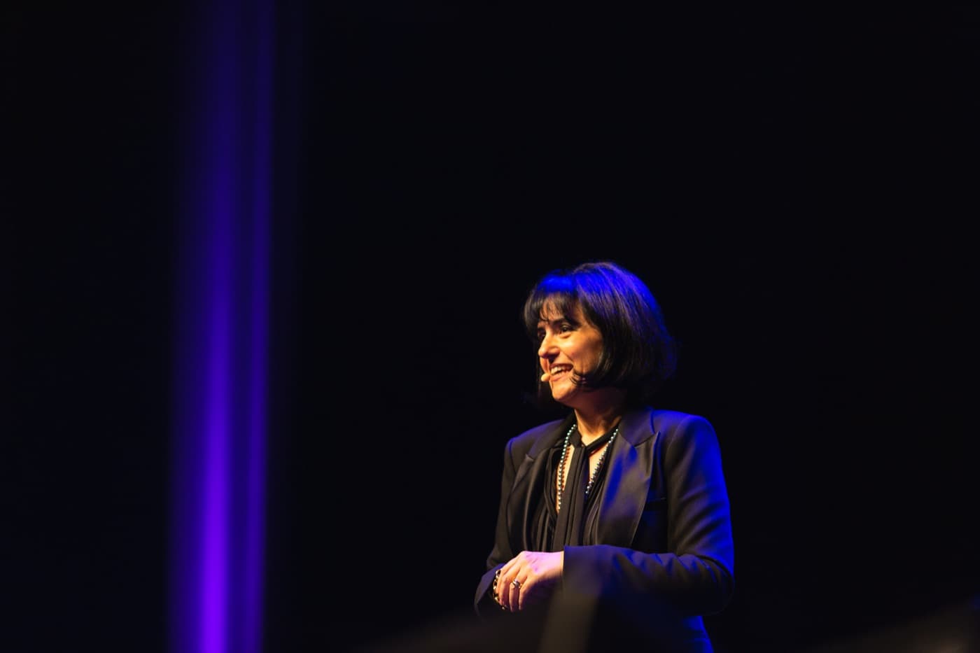 Magali Dardé souriante sur scène avec un micro-casque, lors d'une intervention corporate
